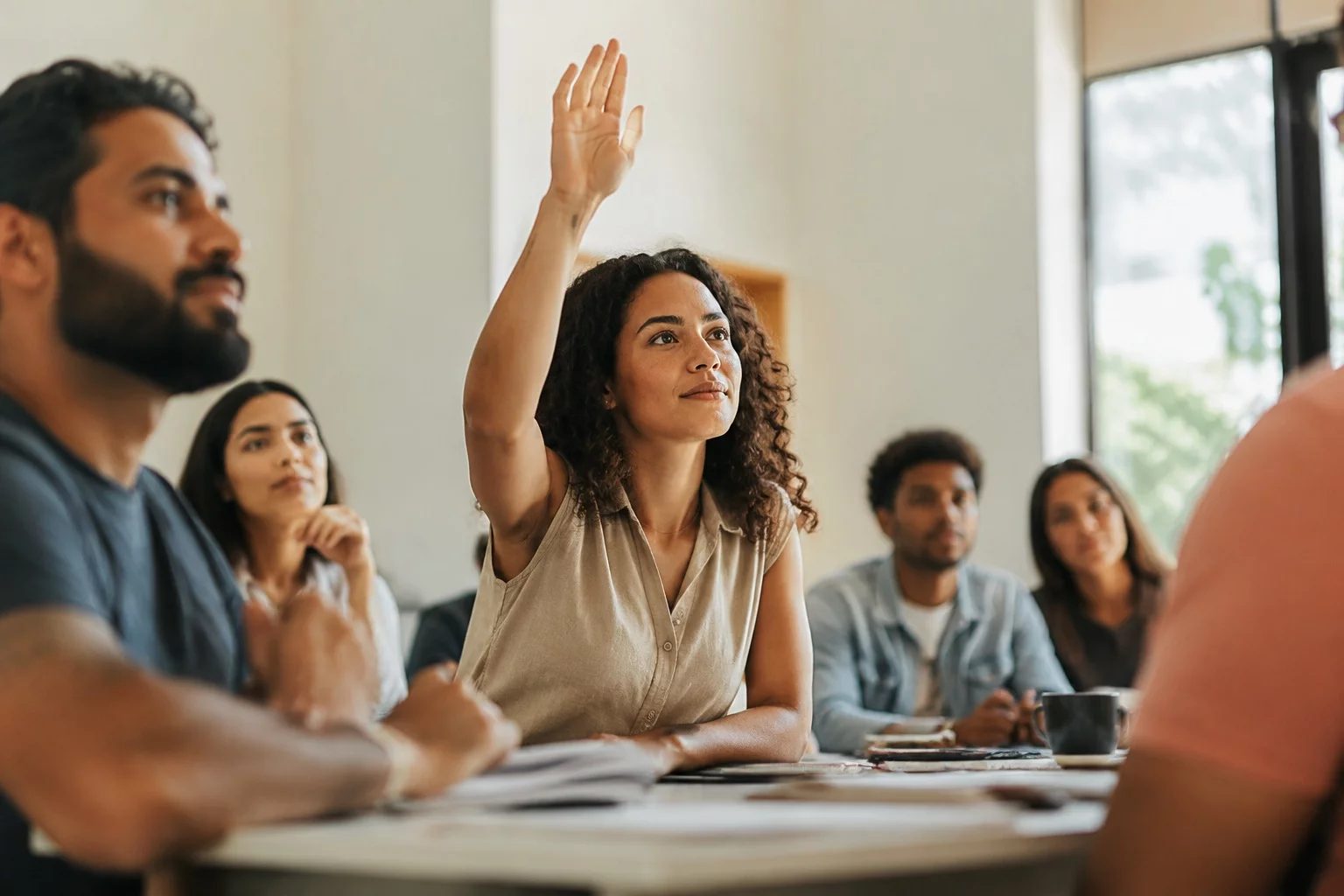 Estudante levantando a mão em uma mesa de seminário coberta de anotações